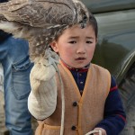 A young future eagle hunter holds a small hawk. The eagle hunting tradition is passed from one generation to another.