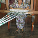 This lady is setting up her loom. The warp strands are still tied together.