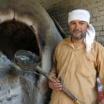 This baker demonstrated how he scoops the hot obi-non out of the oven.