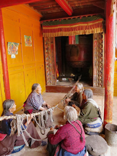 Old Tibetan Women were mending a bell pull rope at their village temple.