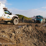 An overloaded truck carrying a mountain of bricks was bogged down and a line of cars was stopped behind it. We could smell the clutch of the stuck truck burning up, wheels spinning in the mud.