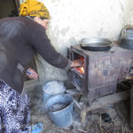 Mom is stoking the cooking stove fire.