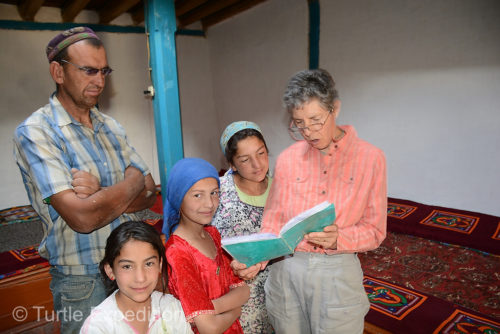 Monika explains a page out of our world atlas, probably pointing out California. Masha (in red) has eyes for the camera.